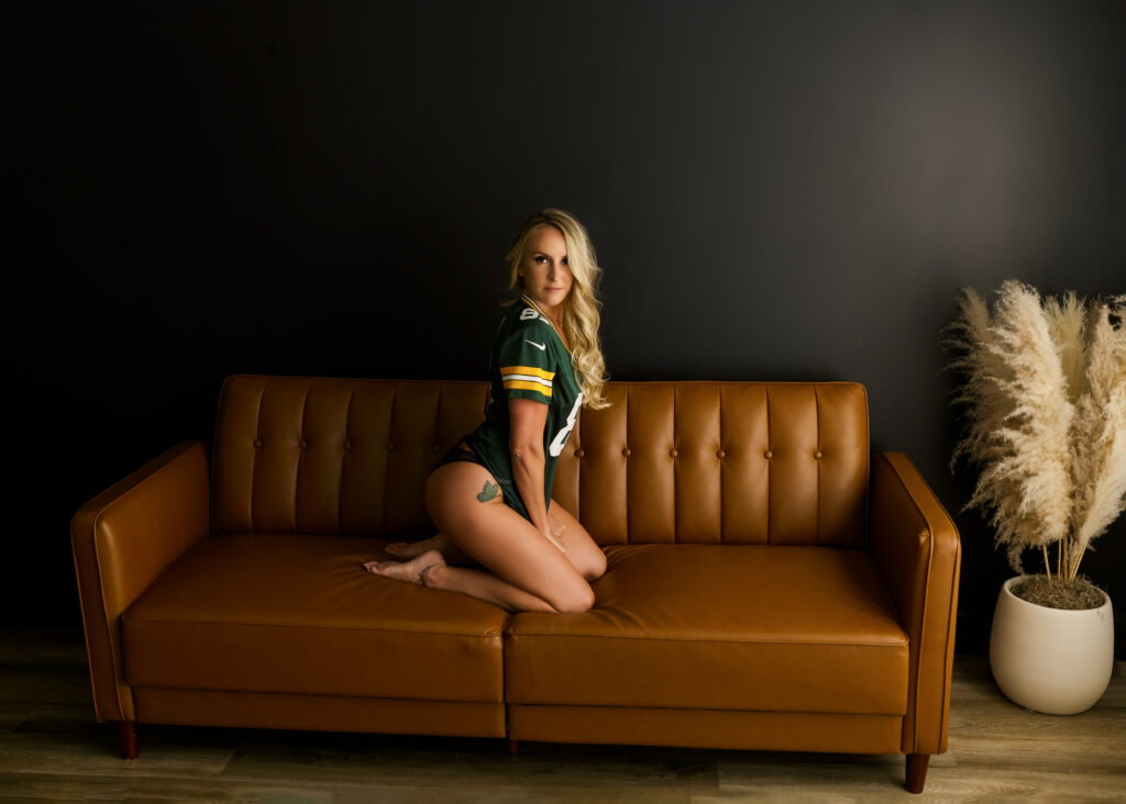 woman posing on couch with jersey during a boudoir session 