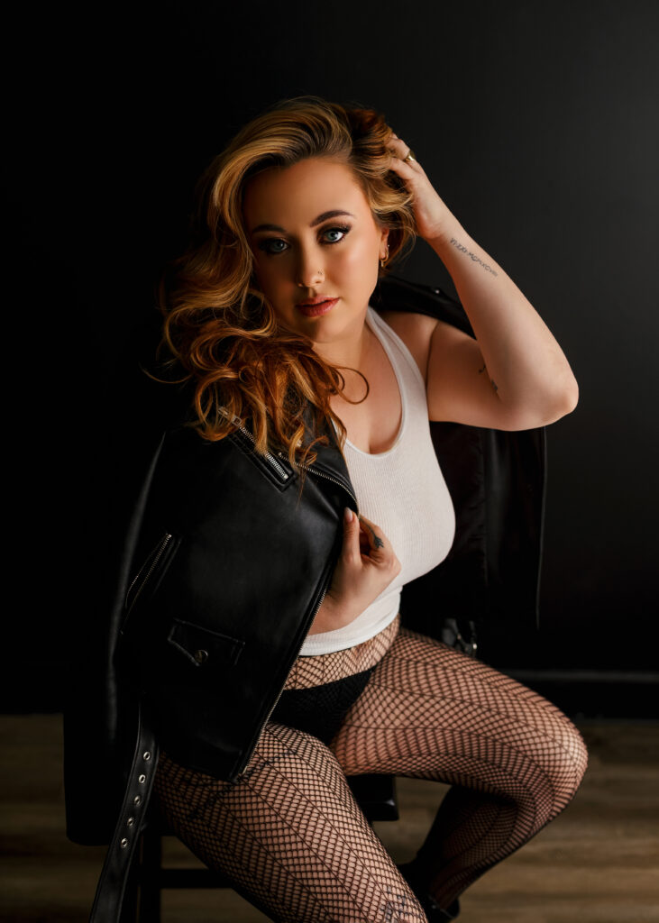 woman posing on stool in leather jacket and fishnets at a boudoir photoshoot in Richmond Virginia 