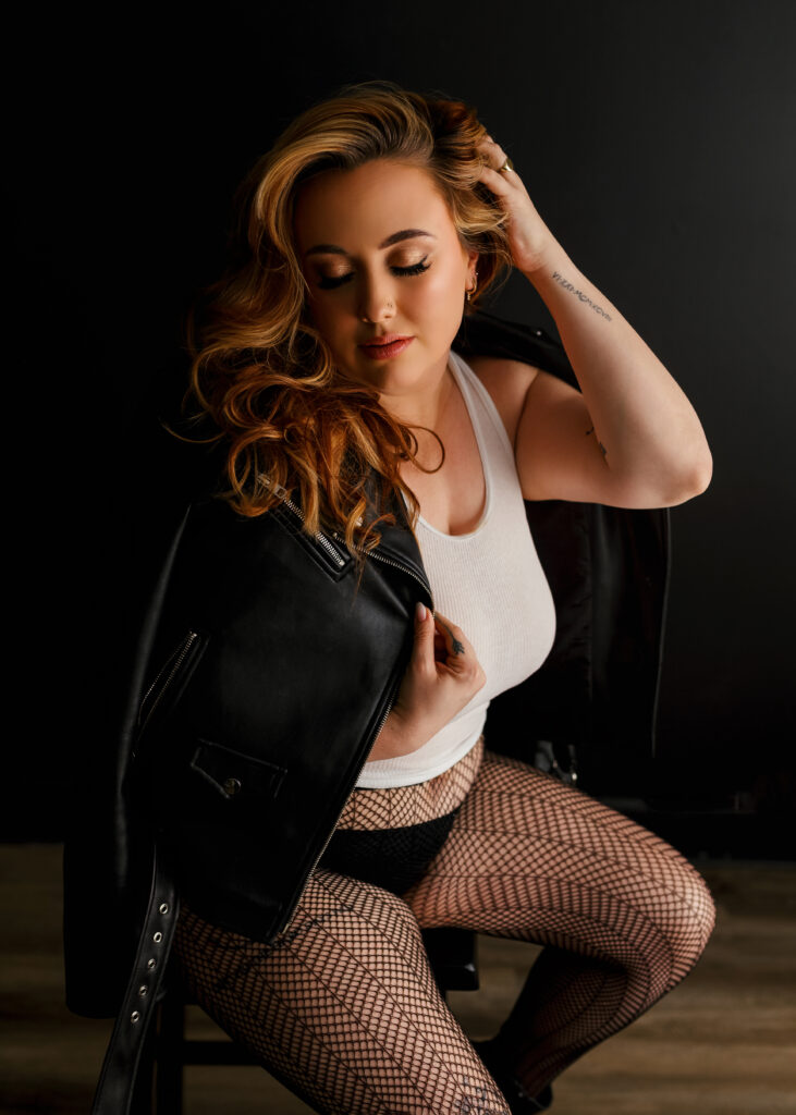 woman posing on stool in leather jacket and fishnets at a boudoir photoshoot in Richmond Virginia 