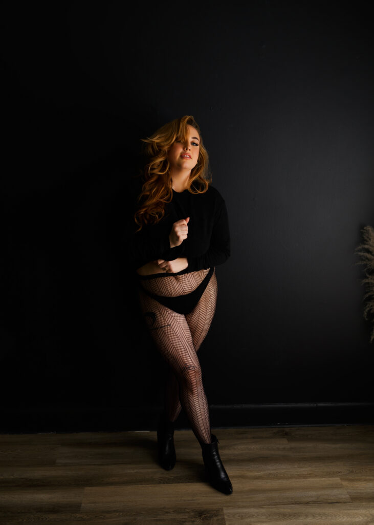 woman in black turtleneck, thong, fishnets and boots posing at a boudoir photoshoot in Richmond Virginia 