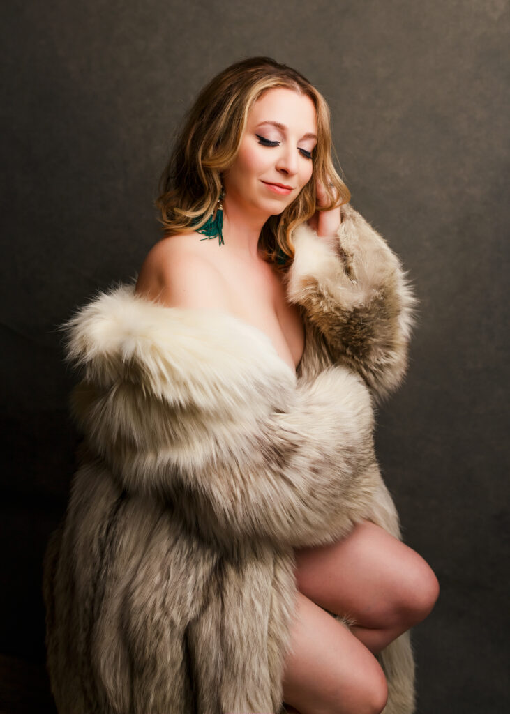 Woman posing in fur coat during her boudoir photoshoot experience in Richmond VA.