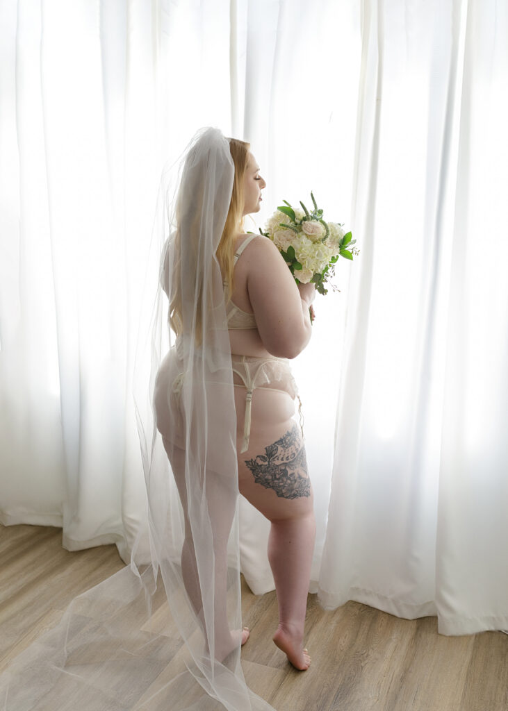 Woman posing in bridal lingerie and spring boutique for bridal boudoir session.
