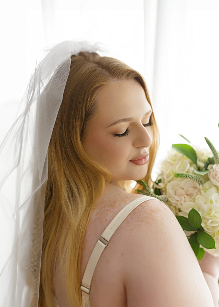 Woman posing in bridal lingerie and spring boutique for bridal boudoir session.