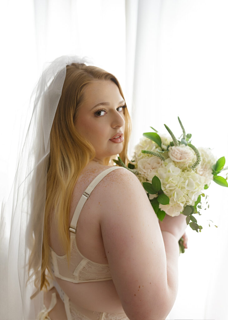 Woman posing in bridal lingerie and spring boutique for bridal boudoir session.